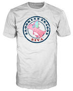 Front view of a white Brooklyn Dragon Diva t-shirt with a pink cartoon dragon inside a large distressed navy circle stamp reading BROOKLYN DRAGON and DIVA in red